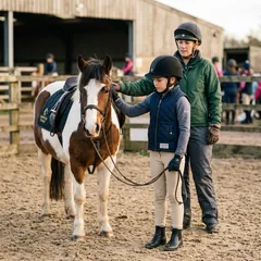 Alumna infantil con pantalón de montar junto a su poni